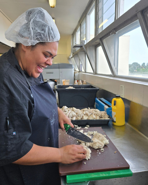 Head Chef Ana chopping chicken, preparing for the lunch rush.